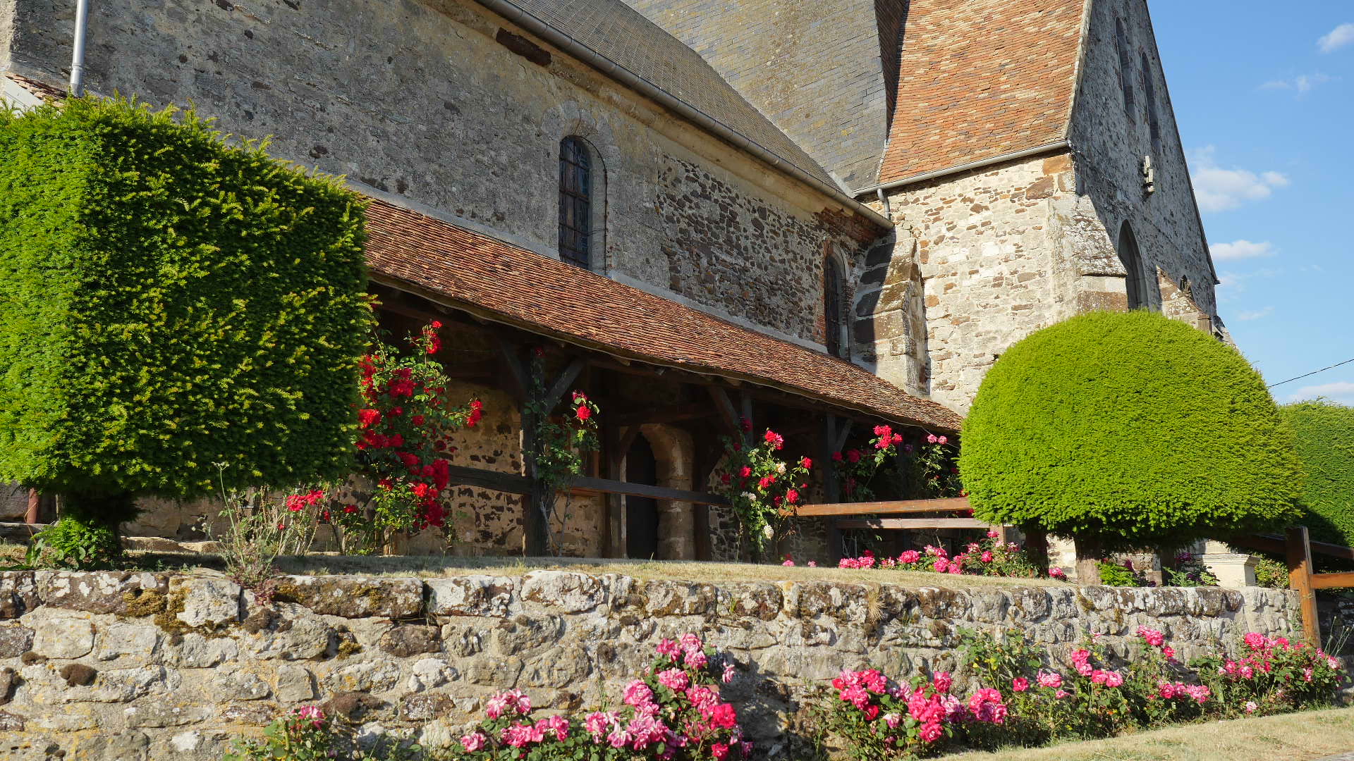 Le porche de l'église avec les rosiers